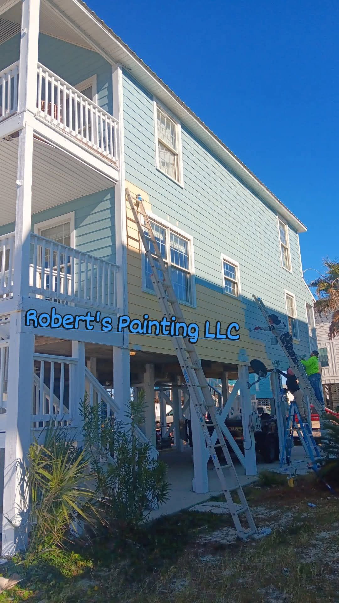 Two-tone coastal home mid-repaint with crew on ladders